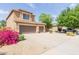 Two-story home with a three-car garage and a long driveway, with desert landscaping and green foliage at 16228 W Crocus Dr, Surprise, AZ 85379