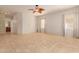 Expansive living room with neutral tile flooring, ceiling fan and ample natural light from large windows at 16228 W Crocus Dr, Surprise, AZ 85379