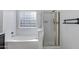 Bright bathroom with a glass shower, soaking tub, and glass block window at 17812 N Carmen Ave, Maricopa, AZ 85139