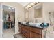Bathroom with granite countertops, double sinks, modern fixtures, walk-in closet, and decorative lighting at 18163 W Addie Ln, Surprise, AZ 85374