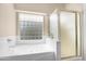 Bright bathroom featuring a soaking tub with jets, a glass-enclosed shower, and tiled walls at 18163 W Addie Ln, Surprise, AZ 85374