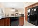 Functional kitchen featuring dark wood cabinets, black appliances, an island and an adjacent dining space at 18163 W Addie Ln, Surprise, AZ 85374