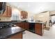 Kitchen with dark wood cabinetry, black countertops, updated appliances, and an open dining area at 18163 W Addie Ln, Surprise, AZ 85374