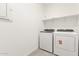 Functional laundry area featuring a washer, dryer, and overhead shelving for organized storage solutions at 24356 W La Salle St, Buckeye, AZ 85326