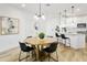 Dining area with a round wooden table, modern light fixture, and seamless transition into the kitchen space at 2511 W Queen Creek Rd # 165, Chandler, AZ 85248