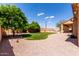 Landscaped backyard with grass, trees, gravel, and a view of the covered patio at 2528 N Ashbrook Cir, Mesa, AZ 85213