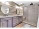 Modern bathroom featuring dual sinks, wood-look tile accent wall and walk-in shower with pebble floor at 3841 E Jasper Dr, Gilbert, AZ 85296