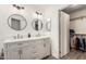 Bathroom featuring a double sink vanity with modern fixtures, round mirrors and access to a walk-in closet at 4128 E Coolbrook Ave, Phoenix, AZ 85032