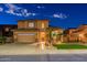 Elegant home at night boasting a well-lit facade, palm trees, and a two-car garage at 4894 E Palm Beach Dr, Chandler, AZ 85249