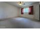 Neutral bedroom has carpet, window with red curtains, a door to the hallway, and a ceiling fan at 601 W 15Th St, Tempe, AZ 85281