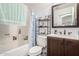 Bathroom with tub shower, storage shelves, framed mirror, and vanity with a faux marble countertop at 6331 W Winslow Ave, Phoenix, AZ 85043