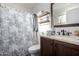 Full bathroom featuring a shower with patterned curtains, wood shelves, and vanity with a faux marble countertop at 6331 W Winslow Ave, Phoenix, AZ 85043