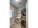 A well-lit laundry room has a modern stacked washer and dryer set, open shelving and a door to the outside at 6801 E Sheena Dr, Scottsdale, AZ 85254