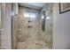 Modern shower with pebble floor, tiled walls, a small window, and a multi-setting shower head at 6801 E Sheena Dr, Scottsdale, AZ 85254