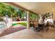 Covered patio with outdoor dining furniture overlooking a manicured backyard and fenced pool at 7402 W Kerry Way, Glendale, AZ 85308