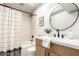 Bright bathroom features wood cabinet, modern fixtures, round mirror and shower over tub at 7467 E Pleasant Run, Scottsdale, AZ 85258