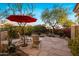 Charming patio area with stone flooring, red umbrella, mature desert landscaping, and seating at 7979 E Princess Dr # 26, Scottsdale, AZ 85255