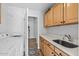 Bright laundry room with cabinets, white counter, deep sink, and view into closet/hallway at 8235 E Sierra Pinta Dr, Scottsdale, AZ 85255