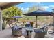 Outdoor patio with multiple seating areas, fire table, umbrellas, and lush desert landscaping at 8235 E Sierra Pinta Dr, Scottsdale, AZ 85255