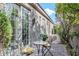 Charming patio with brick pavers, dining set, and lush green foliage near the exterior wall and windows at 8235 E Sierra Pinta Dr, Scottsdale, AZ 85255