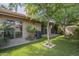 Lush backyard with mature shade trees, grassy area, and access to the home through large sliding glass doors at 945 N Pasadena -- # 84, Mesa, AZ 85201