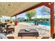 Covered patio area with brick pavers, wicker furniture, a view of the pool and backyard with waterfall feature at 2017 E Willis Rd, Gilbert, AZ 85297