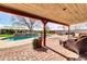 Covered patio area with brick pavers, wicker furniture, and view of pool with rock waterfall feature at 2017 E Willis Rd, Gilbert, AZ 85297