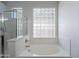 Bright bathroom featuring a soaking tub, a glass-block window, and a glass-enclosed shower at 2620 W Piedmont Rd, Phoenix, AZ 85041