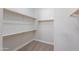 Spacious walk-in closet featuring white walls, wood shelving and rods, and carpeted flooring at 2620 W Piedmont Rd, Phoenix, AZ 85041