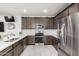 Well-equipped kitchen with stainless steel appliances, quartz countertops, modern backsplash, and dark wood cabinets at 2640 N Heritage St, Buckeye, AZ 85396