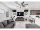 Inviting living room featuring a large gray couch, ceiling fan, mounted TV, and easy access to the kitchen and breakfast bar at 2640 N Heritage St, Buckeye, AZ 85396