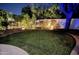 A backyard featuring a circular lawn, lush landscaping, a tree, and a charming flower bed set against a white wall at 8332 E San Simon Dr, Scottsdale, AZ 85258