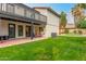 A spacious backyard featuring a lush lawn, patio, and a second story balcony, with mature trees and landscaping at 10775 N 101St St, Scottsdale, AZ 85260