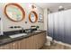 Bathroom featuring double sinks with wood-look cabinets and round mirrors plus a shower with curtain at 10775 N 101St St, Scottsdale, AZ 85260