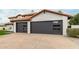 A house with a large driveway, with dark gray garages featuring contemporary window accents at 10775 N 101St St, Scottsdale, AZ 85260