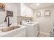 Bright laundry room featuring modern appliances, white cabinets and a sink at 10775 N 101St St, Scottsdale, AZ 85260