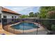 Backyard view of a private pool with a safety fence and surrounding patio, along with green landscaping at 10775 N 101St St, Scottsdale, AZ 85260