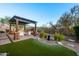 Outdoor living space with fireplace, pergola, seating, and well-manicured landscaping at 6887 E Hacienda La Colorada Dr, Gold Canyon, AZ 85118