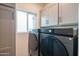 Modern laundry room featuring front-load washer and dryer, sleek cabinets, and a bright window at 2030 E Michigan Ave # 4, Phoenix, AZ 85022