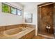 The bathroom features a glass shower, a soaking tub with a tray, earth-tone tile, and a window at 7701 E Golden Eagle Cir, Gold Canyon, AZ 85118