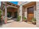Inviting front entrance featuring a stone facade, covered patio, and a solid wood door with a Welcome mat at 7701 E Golden Eagle Cir, Gold Canyon, AZ 85118