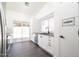 Modern kitchen with white cabinets, hardwood floors, stainless steel appliances, and access to the backyard at 11343 W Mccaslin Rose Ln, Surprise, AZ 85378