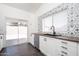 Bright kitchen features white cabinets, stylish backsplash, stainless steel appliances, and backyard access at 11343 W Mccaslin Rose Ln, Surprise, AZ 85378