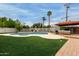 Backyard oasis featuring a sparkling pool, lush landscaping, and comfortable lounging area at 1316 E Vermont Ave, Phoenix, AZ 85014