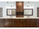 Bathroom with dual sinks, framed mirrors, dark cabinets, and custom wine storage at 14814 N Coral Gables Dr, Phoenix, AZ 85023