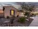 Charming home exterior at twilight showcasing a desert landscaped yard and a well-lit garage at 18033 W Tecoma Rd, Goodyear, AZ 85338