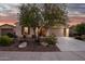 Inviting home exterior showcasing desert landscaping, mature trees, and an attached two-car garage in an evening setting at 18033 W Tecoma Rd, Goodyear, AZ 85338