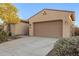 Beige single Gathering home featuring a spacious two car garage and concrete driveway at 18033 W Tecoma Rd, Goodyear, AZ 85338