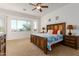 Spacious main bedroom with large window, ceiling fan, carpet flooring, and stylish furniture at 18033 W Tecoma Rd, Goodyear, AZ 85338
