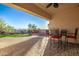 This covered patio features brick pavers, bar height seating, and views of the lush green backyard at 18033 W Tecoma Rd, Goodyear, AZ 85338